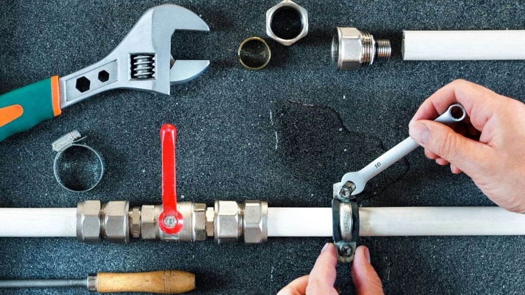 Plumber repairing a pipe valve with an adjustable wrench in Lakeland