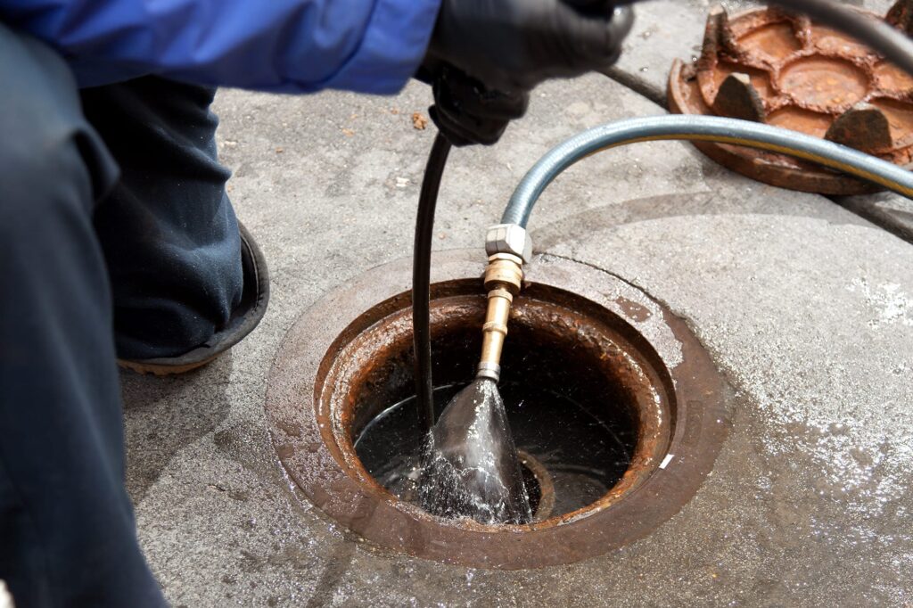 Plumber hydro jetting a sewer line through a manhole in Lakeland