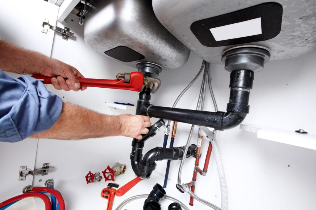 Plumber repairing drain pipes beneath a kitchen sink in Lakeland