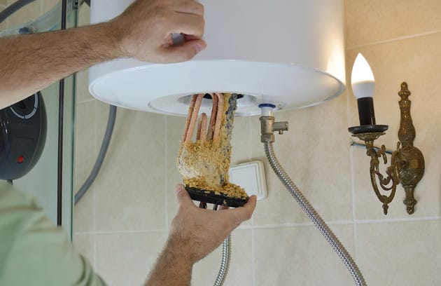 Technician removing mineral buildup from a water heater in Lakeland
