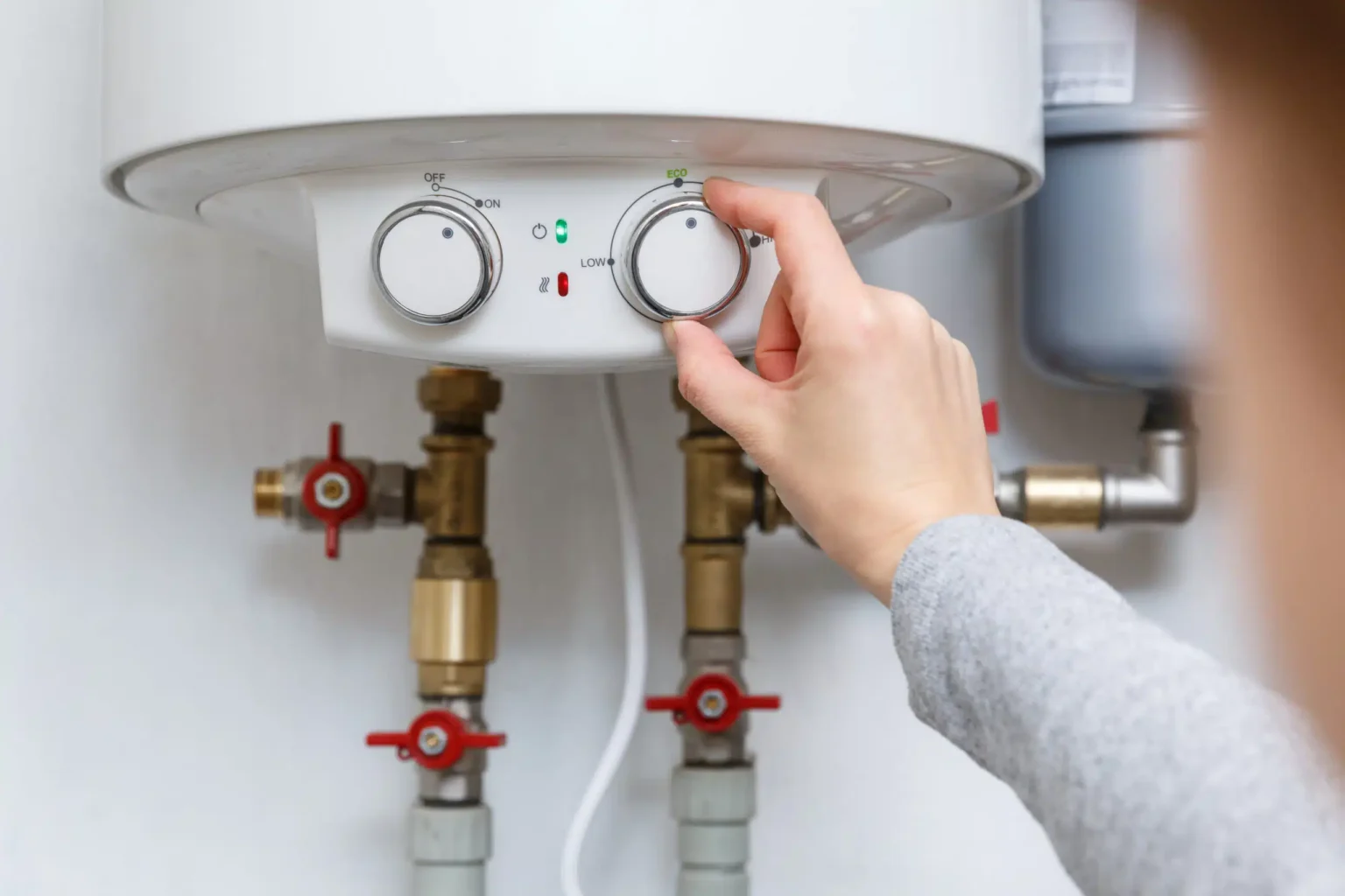 Homeowner adjusting the temperature controls on a water heater in Lakeland